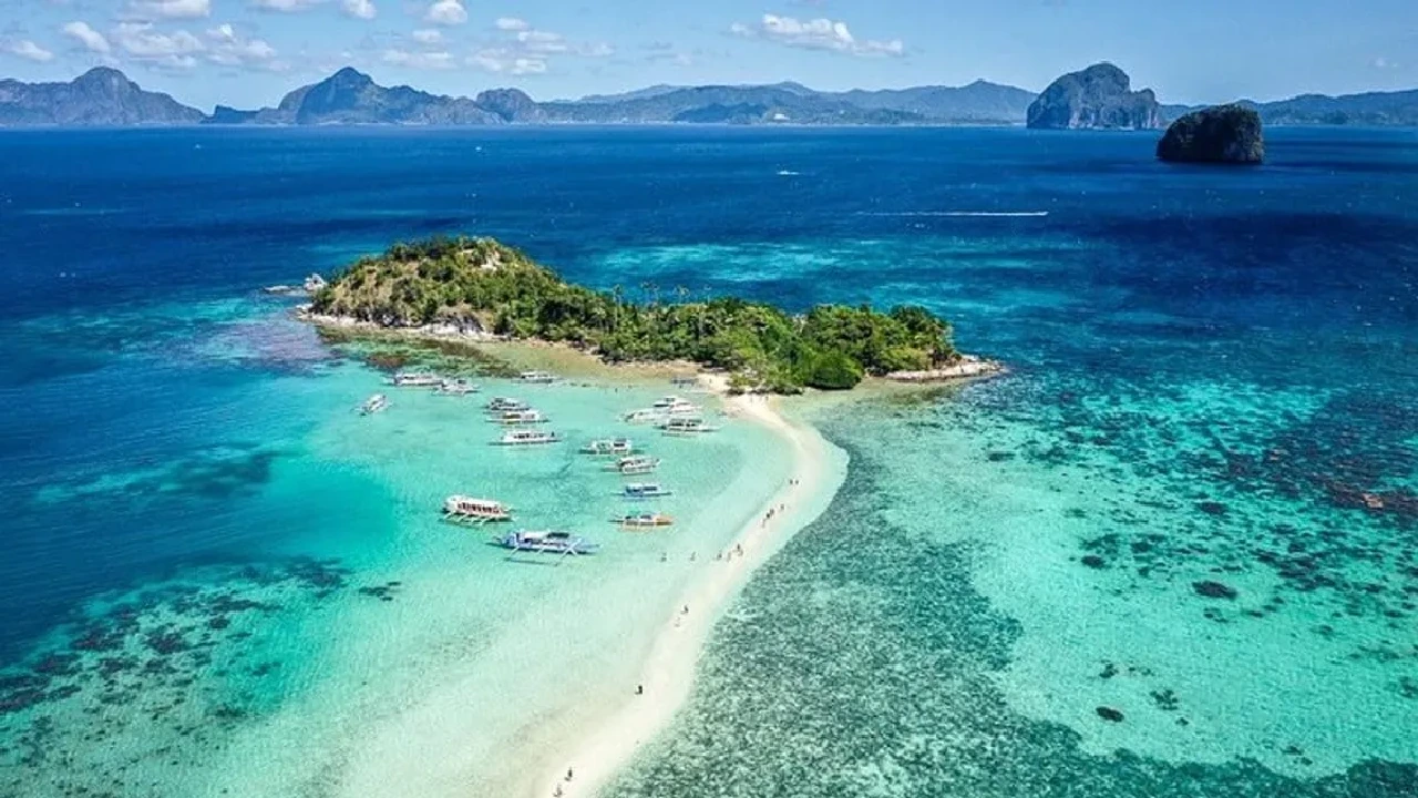 Aerial view of the winding white sandbar of Snake Island, El Nido, with tour boats moored in the shallows