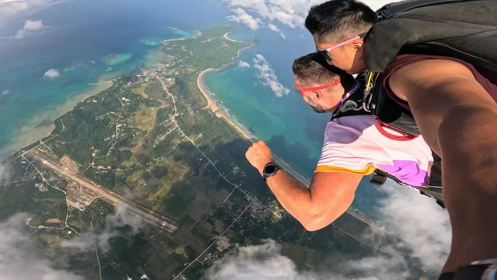 Tandem skydivers in freefall above San Vicente town, its airstrip and Long Beach